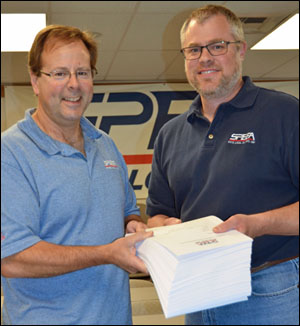 SPEEA’s Rich Plunkett, left, and Matt Kempf hold more than 400 of the “make whole” awards Boeing was ordered to pay employees by an arbitrators ruling. Each sheet represents an award of at least $100,000. For more than a decade, Boeing denied engineers and technical workers at Edwards Air Force Base and in Palmdale the better wages and benefits provided by SPEEA contracts